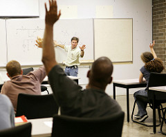 classroom setting with instructor and student raising hand