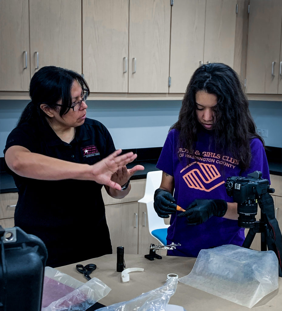Christine Ramirez demonstrates fingerprint photography techniques to student Martha Castillo