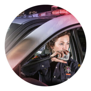 A female officer is talking on her radio in a squad car.