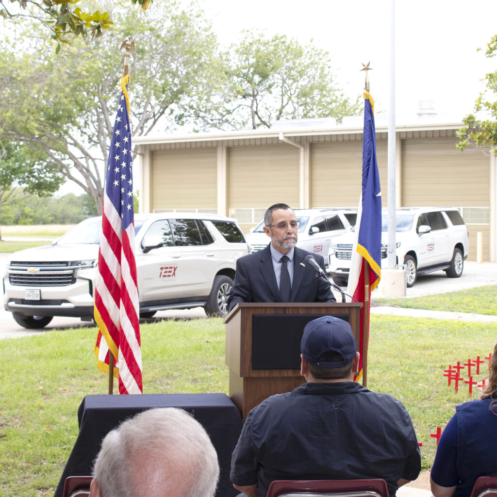 Man speaking at a podium next to the United States and Texas flag