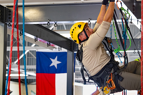 A TEEX SPRAT participant practices rope access techniques while suspended on the training structure.