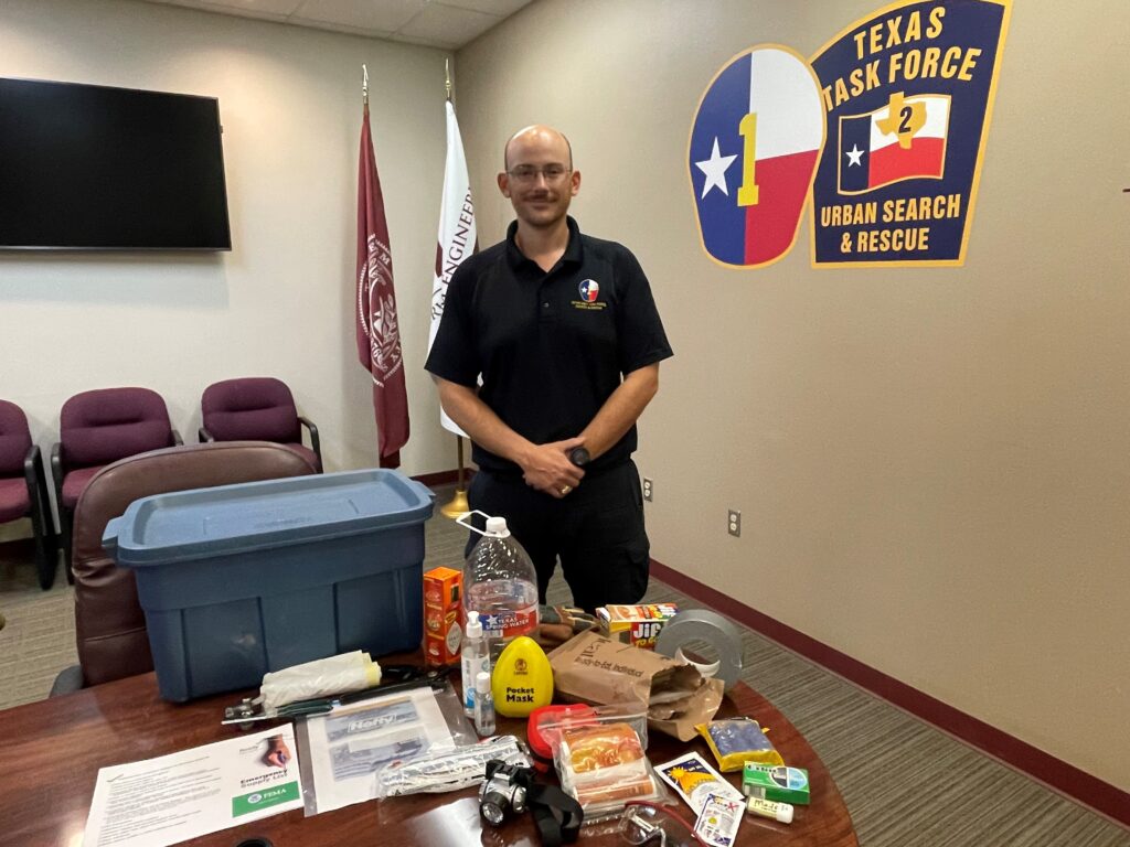 Man standing in front of a desk full of survival kit items