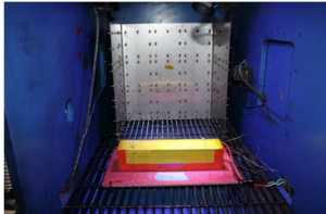 Inside view of blast chamber with Li-ion battery in the foreground and PPE testing rack in the background.