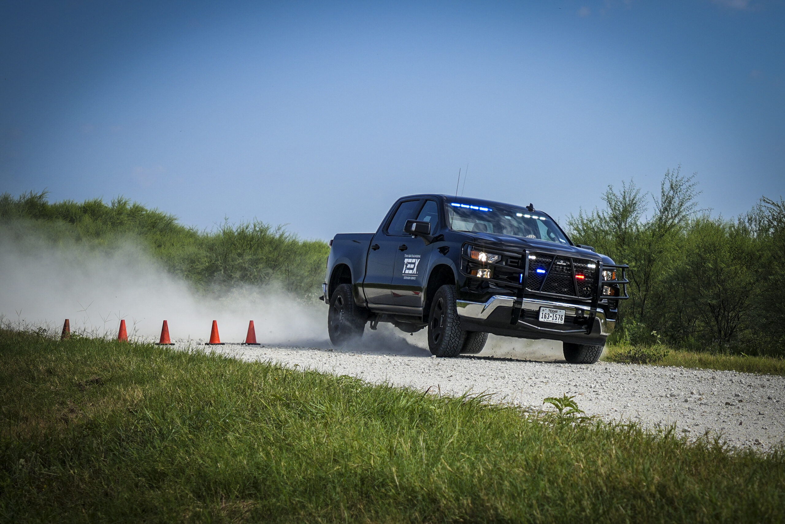 Truck driving on gravel surface at high speeds around obstacle