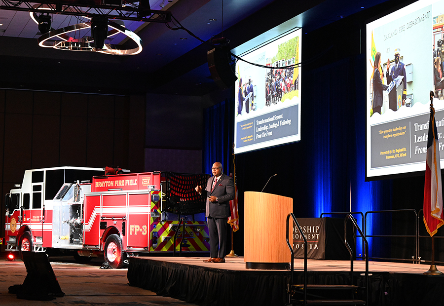 firetruck next to a stage with a man speaking on the stage