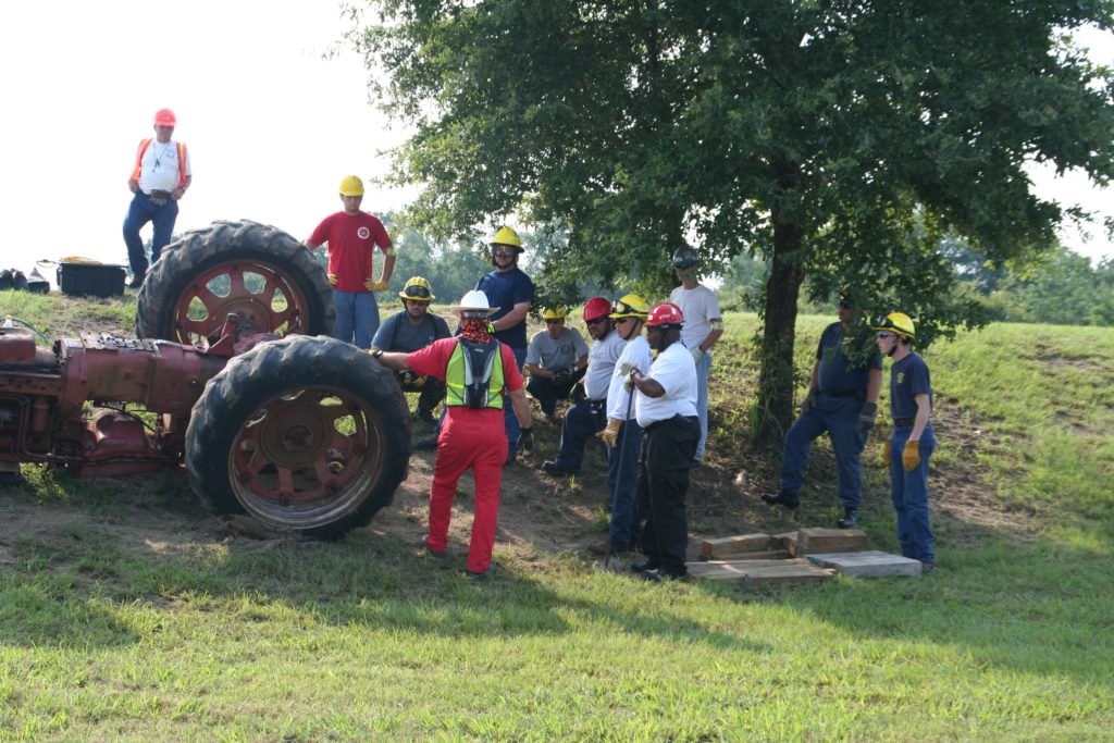 Group of people looking at tractor near a tree in a field