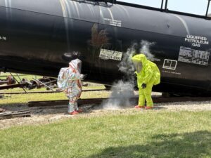 two people in hazmat suites near a train