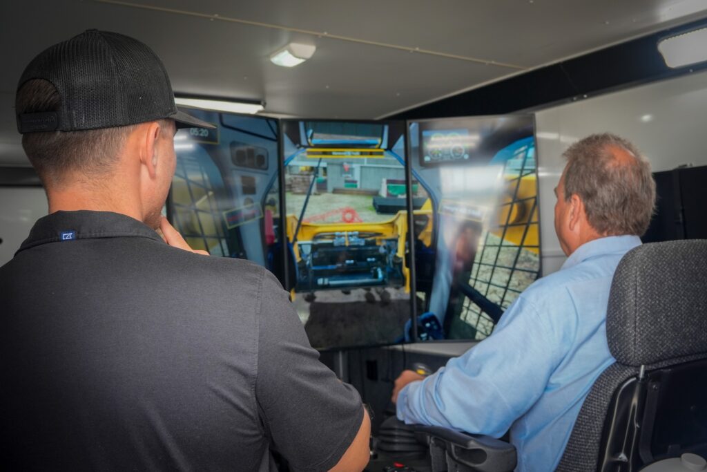 Employees demonstrate how to use the heavy equipment simulator. 