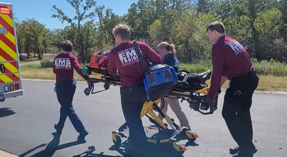 Paramedic students loading an occupied stretcher onto the program’s ambulance
