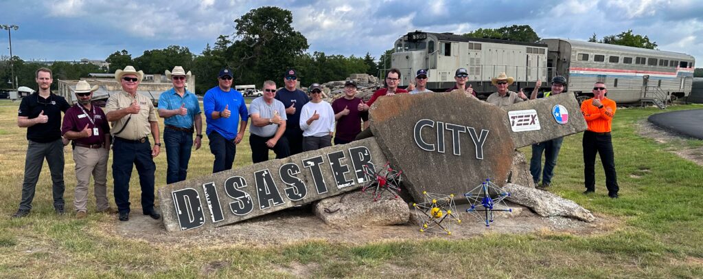 A group of people standing in front of trains and Disaster City sign on rocks