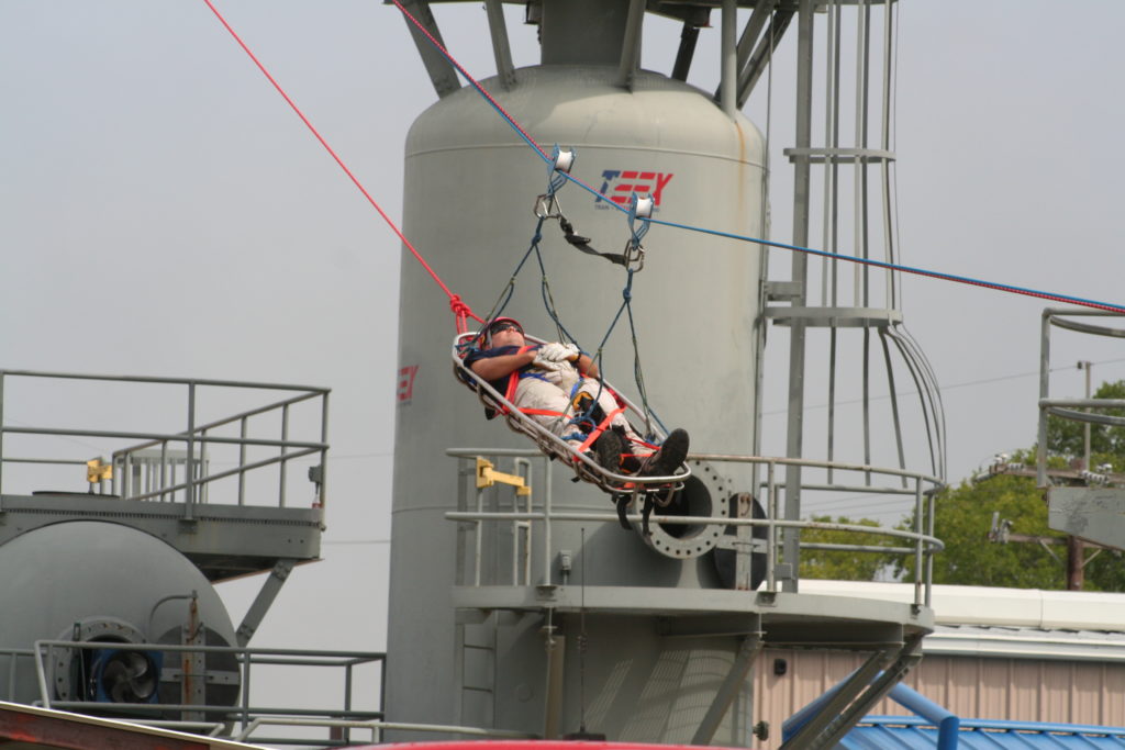 person is rescued with ropes near a large metal container