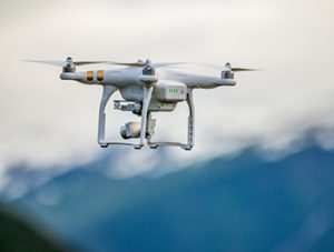 White drone flying above mountains.