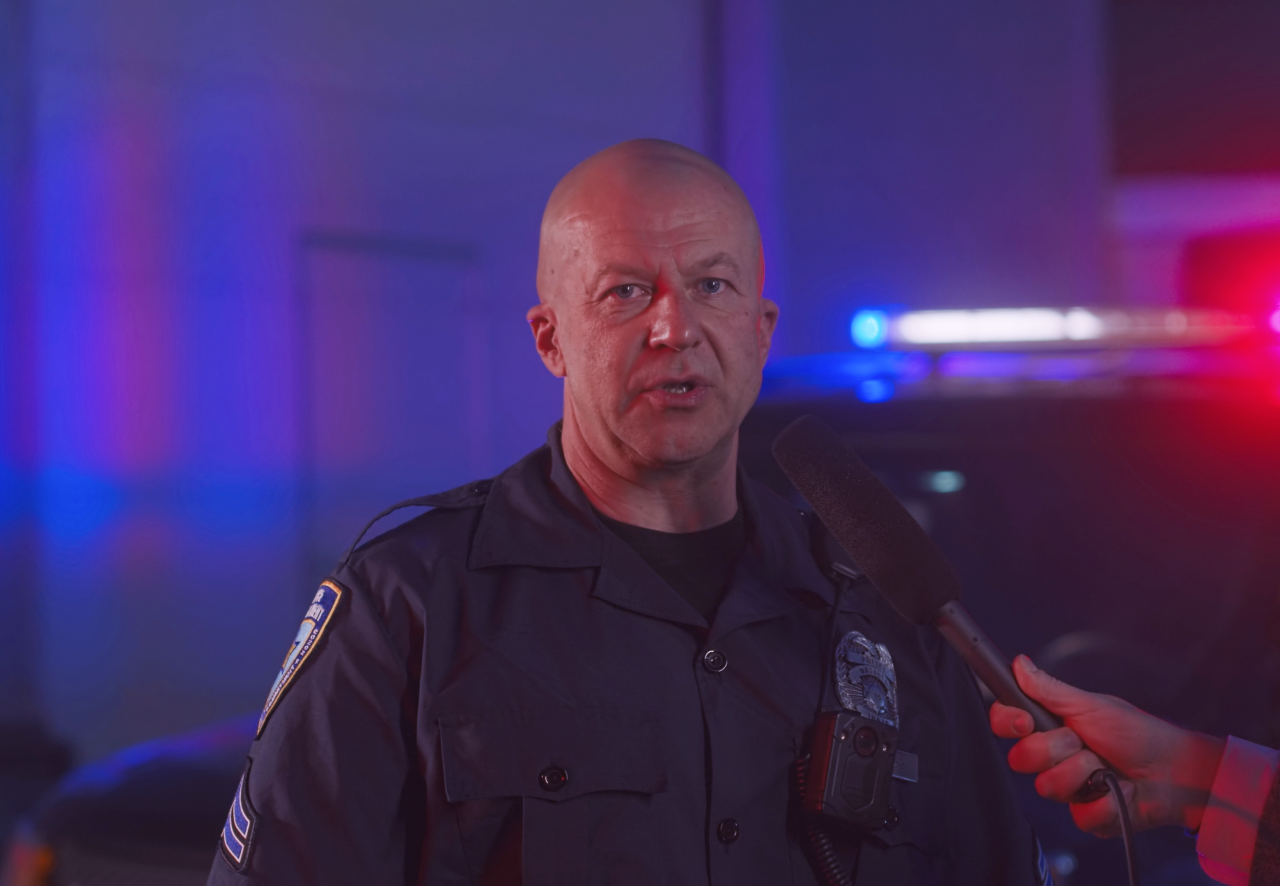 Male law enforcement officer speaking to a reporter at the scene