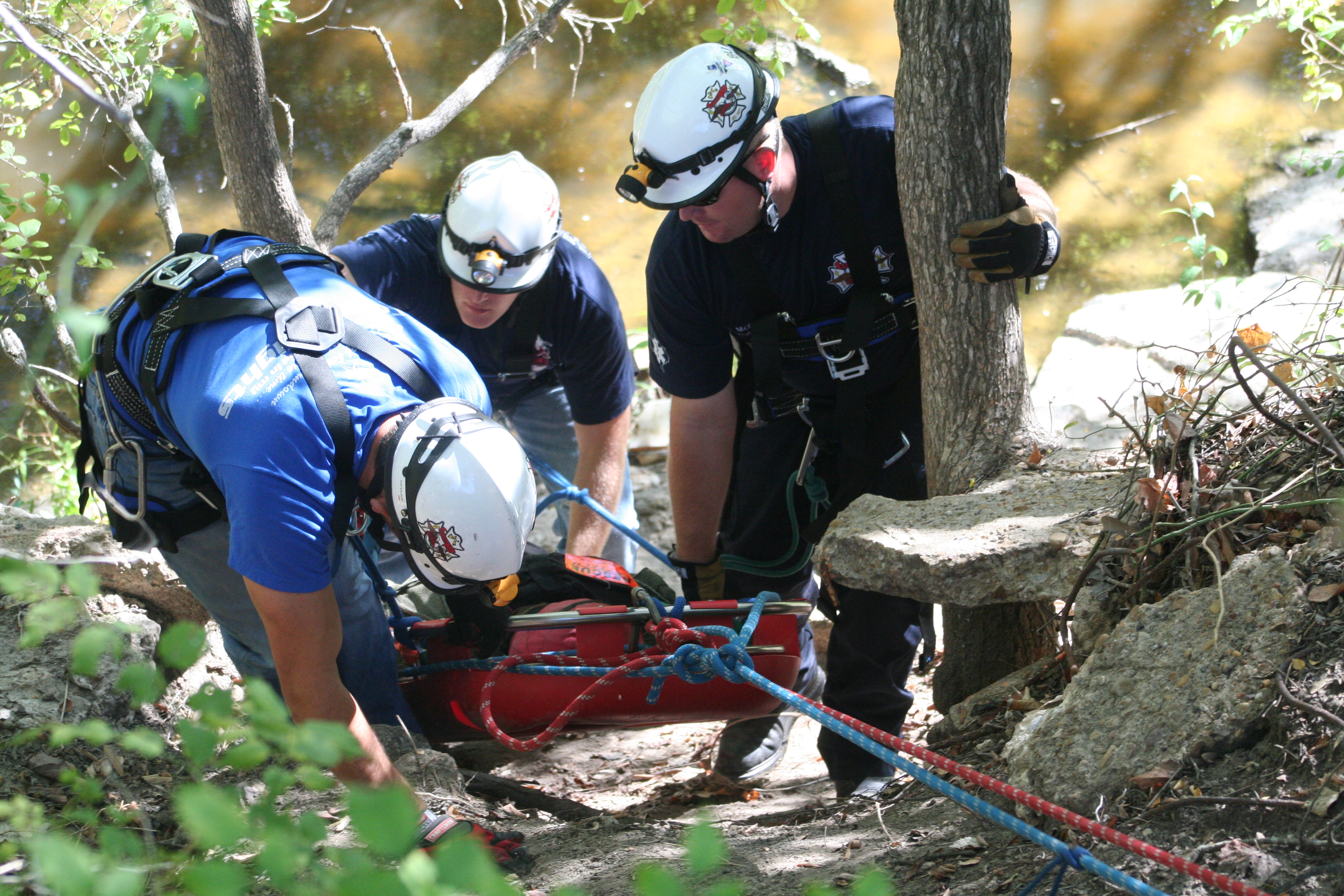 man is rescued by two men from a rocky terrain in the wilderness